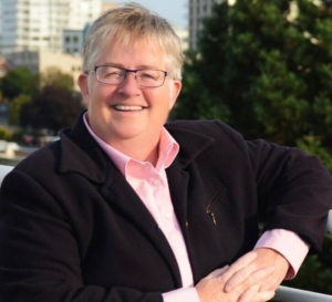 A photo of Mayor Alto wearing a black suit jacket and pink shirt. The photo is taken outside, where buildings and trees are visible.